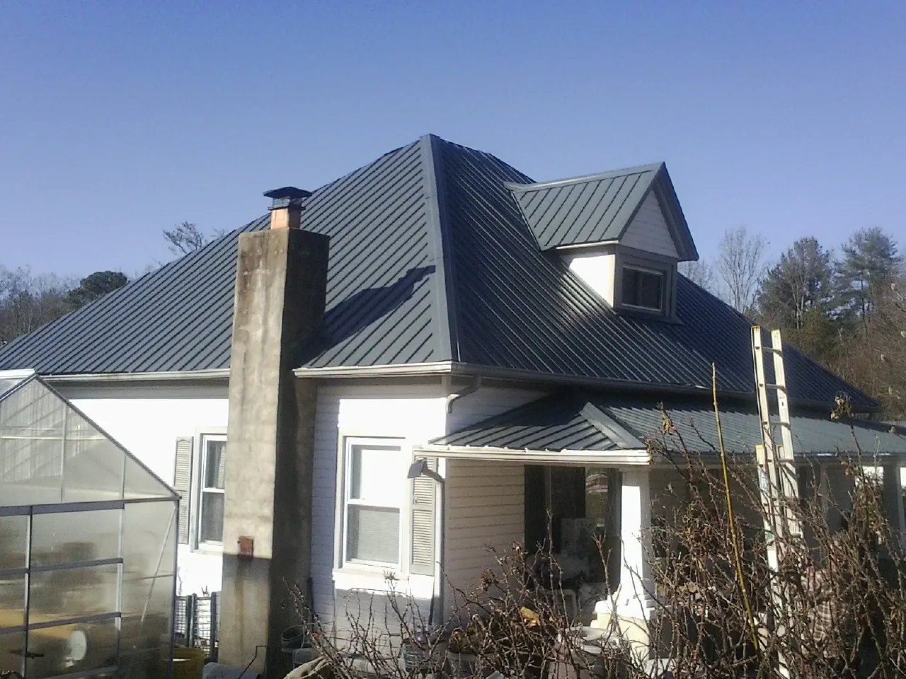 Dark blue standing seam metal roof on a white farmhouse with dormer — Slate & Tile Roof Repair by Roofing Brothers in Christiansburg