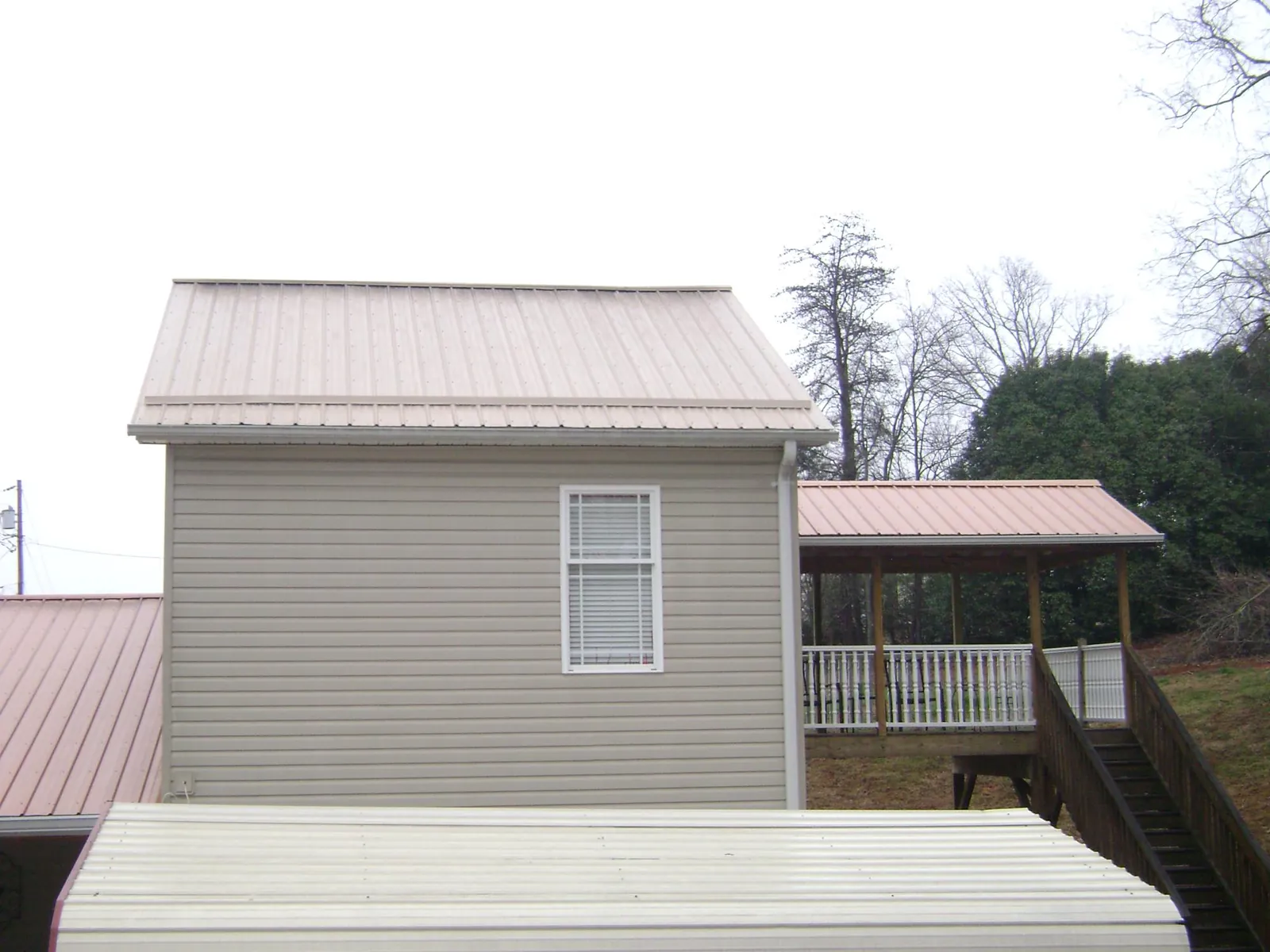 Tan metal roofs on a two story addition and attached porch, from a Roof Replacement job in Christiansburg
